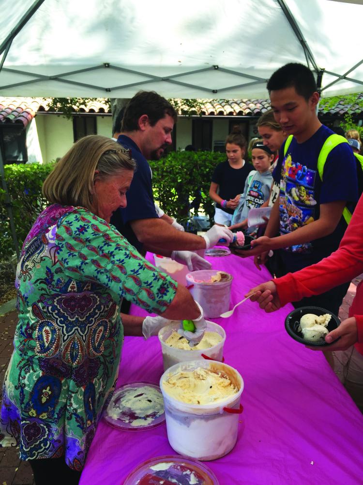 Senior Roth Yin waits in line as Chris Davis and Kevin Shertzer serve scoops of ice cream to students. 